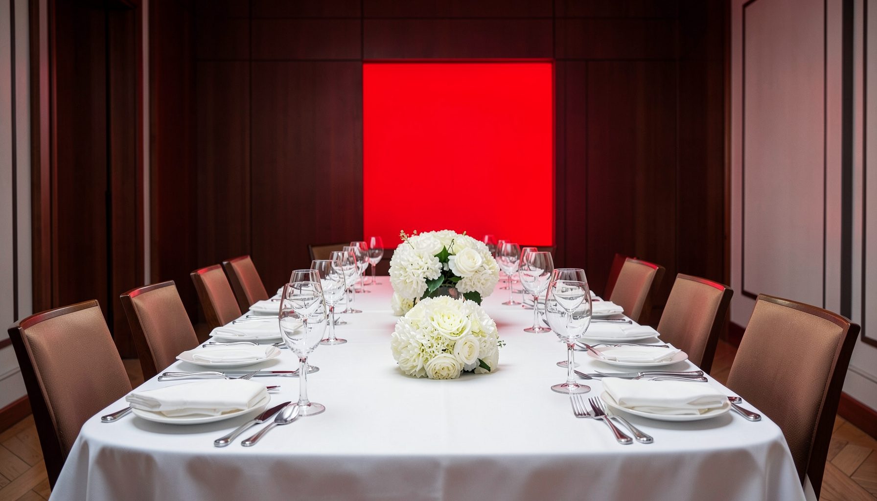 Comedor formal con mantelería impecable, cubiertos dispuestos según protocolo y centro de flores blancas.