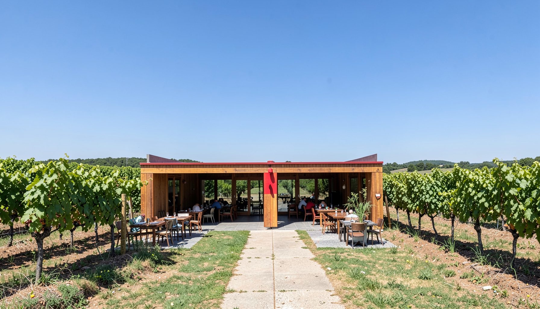 Restaurante de campo con terraza abierta, rodeado de viñedos bajo un cielo despejado de La Mancha.
